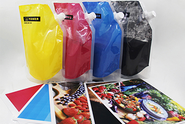 Color toner powder spread across white paper for a close view of CMYK material behavior