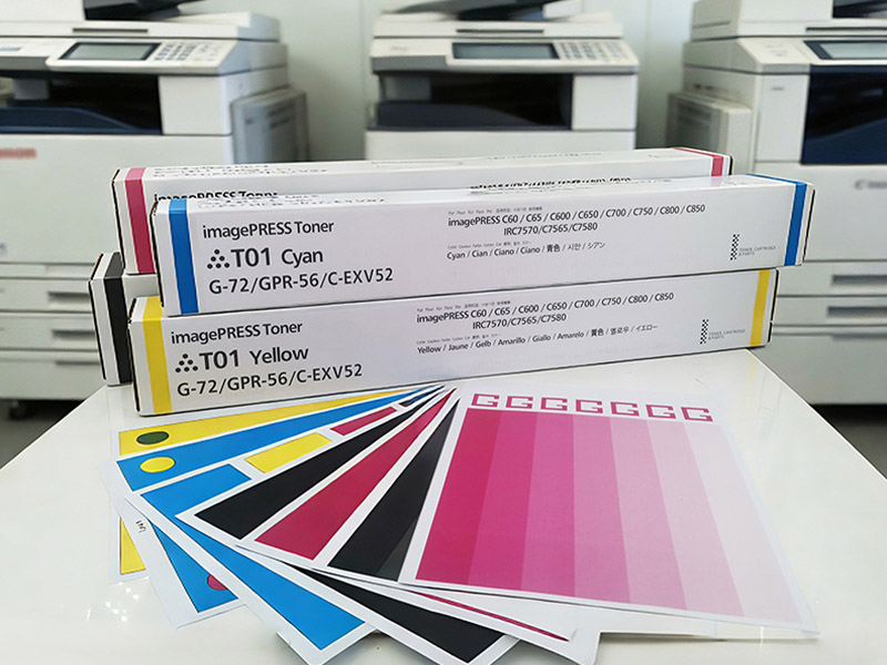 Color toner testing workstation with a laser printer, cartridges, test sheets, and measuring tools